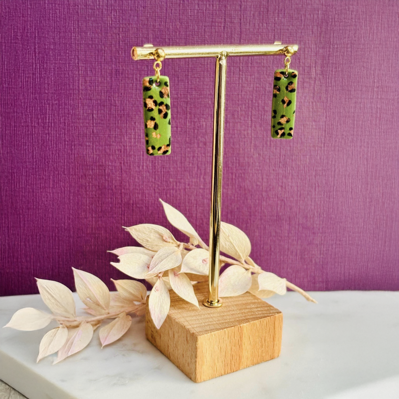 Elegant leopard print drop earrings with gold foil accents, hand-painted and handmade with polymer clay.