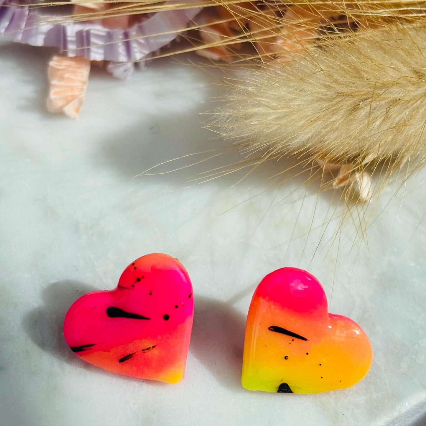 Vibrant 80s disco-inspired heart-shaped stud earrings, handmade with polymer clay. Features a bold color palette with yellow, pink, and black ink splatter.
