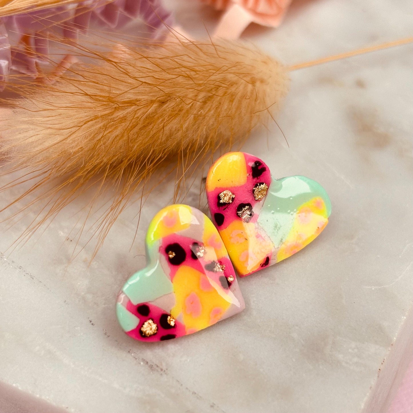 Chic heart-shaped stud earrings with a hand painted leopard print, handmade with polymer clay.