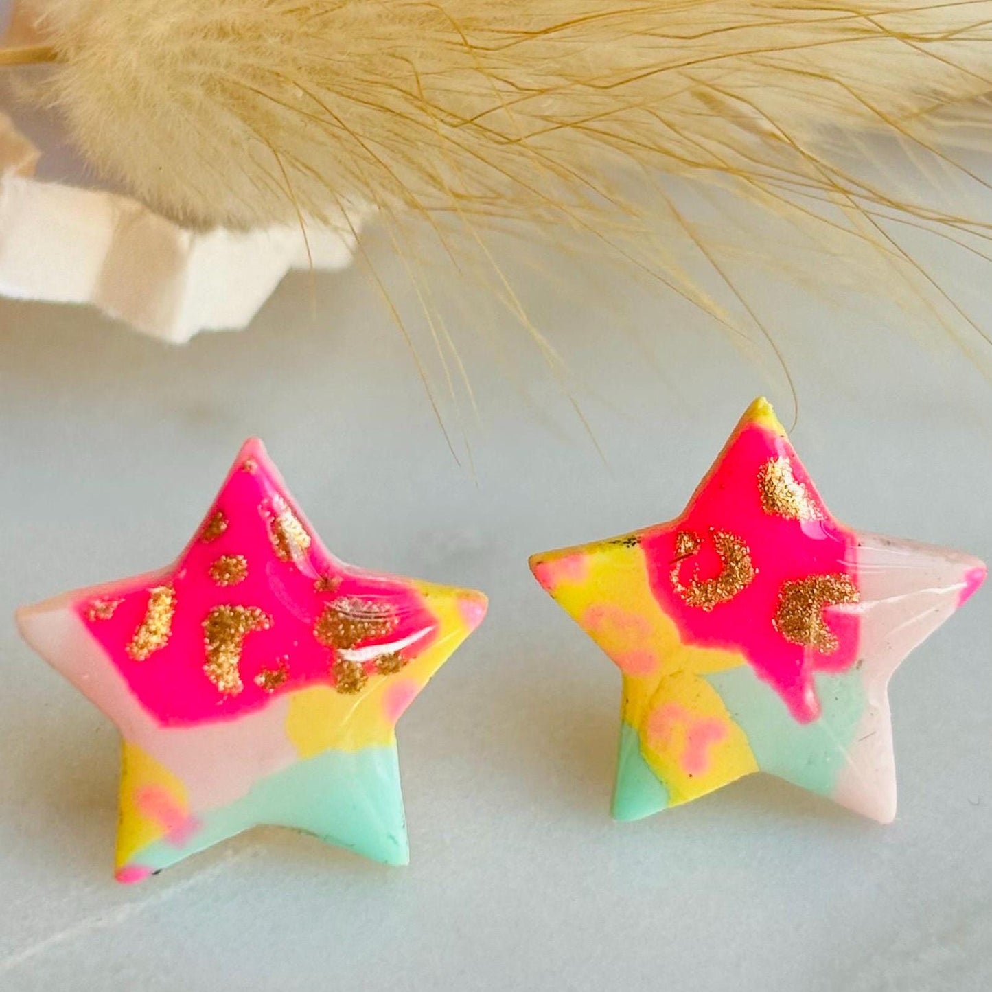Vibrant 90s-inspired star-shaped stud earrings, handmade with polymer clay. Features a bold leopard print pattern and a mix of vibrant colours.