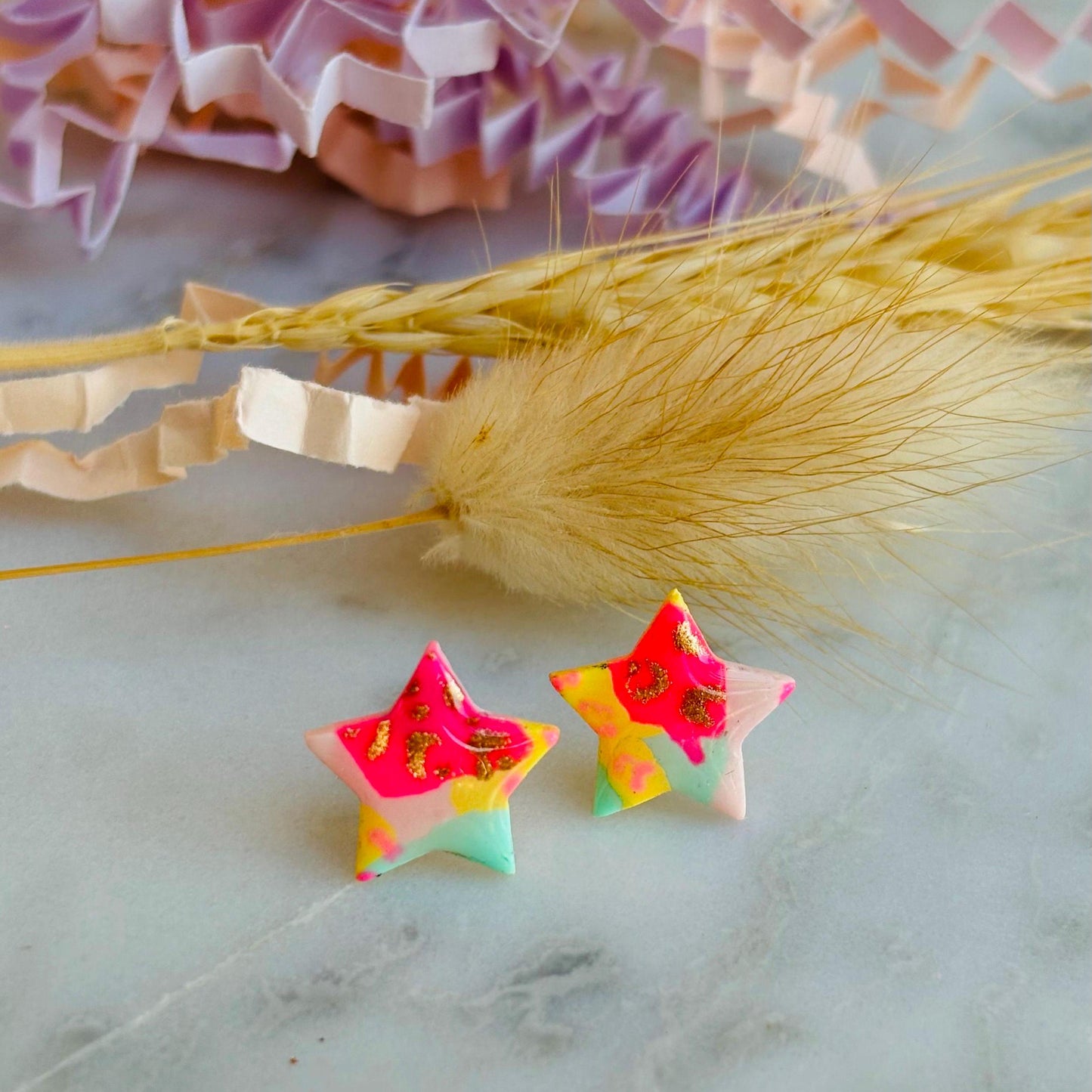 Vibrant 90s-inspired star-shaped stud earrings, handmade with polymer clay. Features a bold leopard print pattern and a mix of vibrant colours.