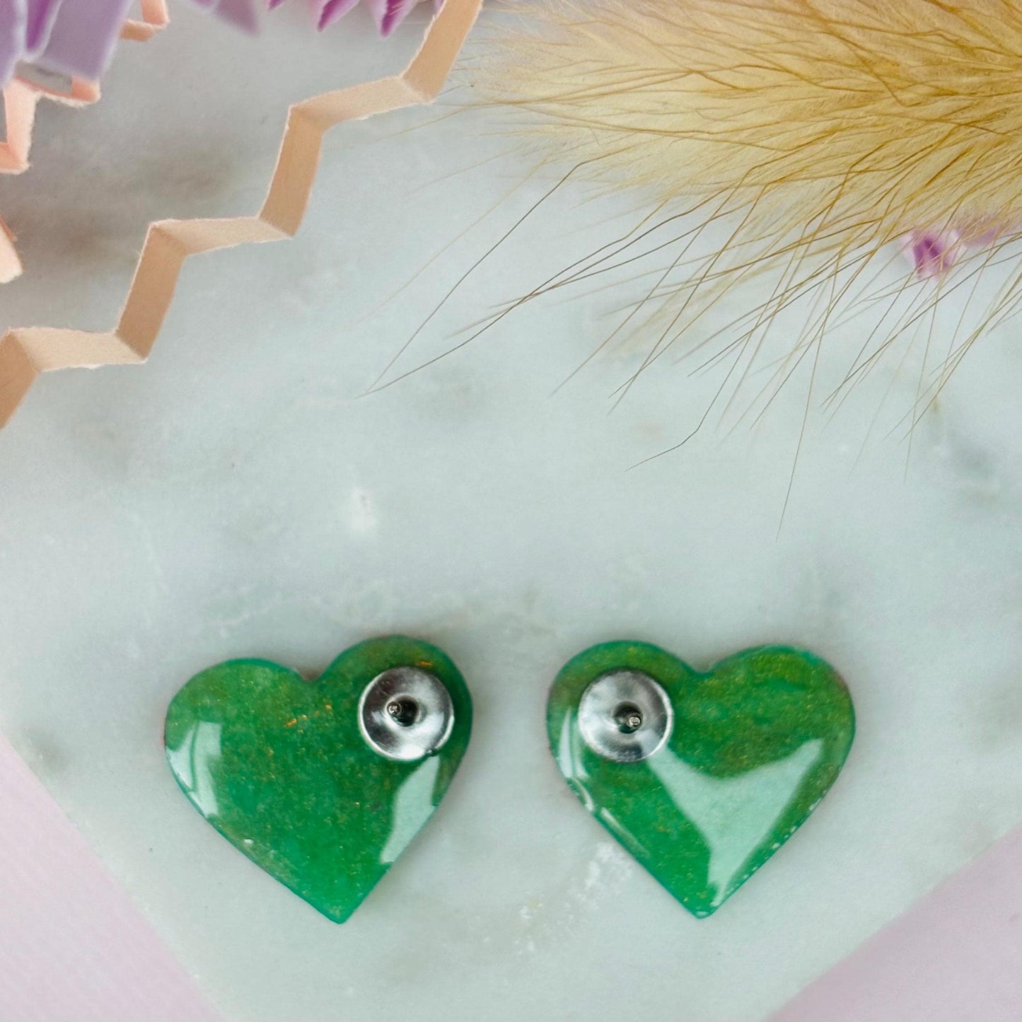 Vibrant neon pink heart-shaped stud earrings, handmade with polymer clay. Features an abstract design with gold foil accents.