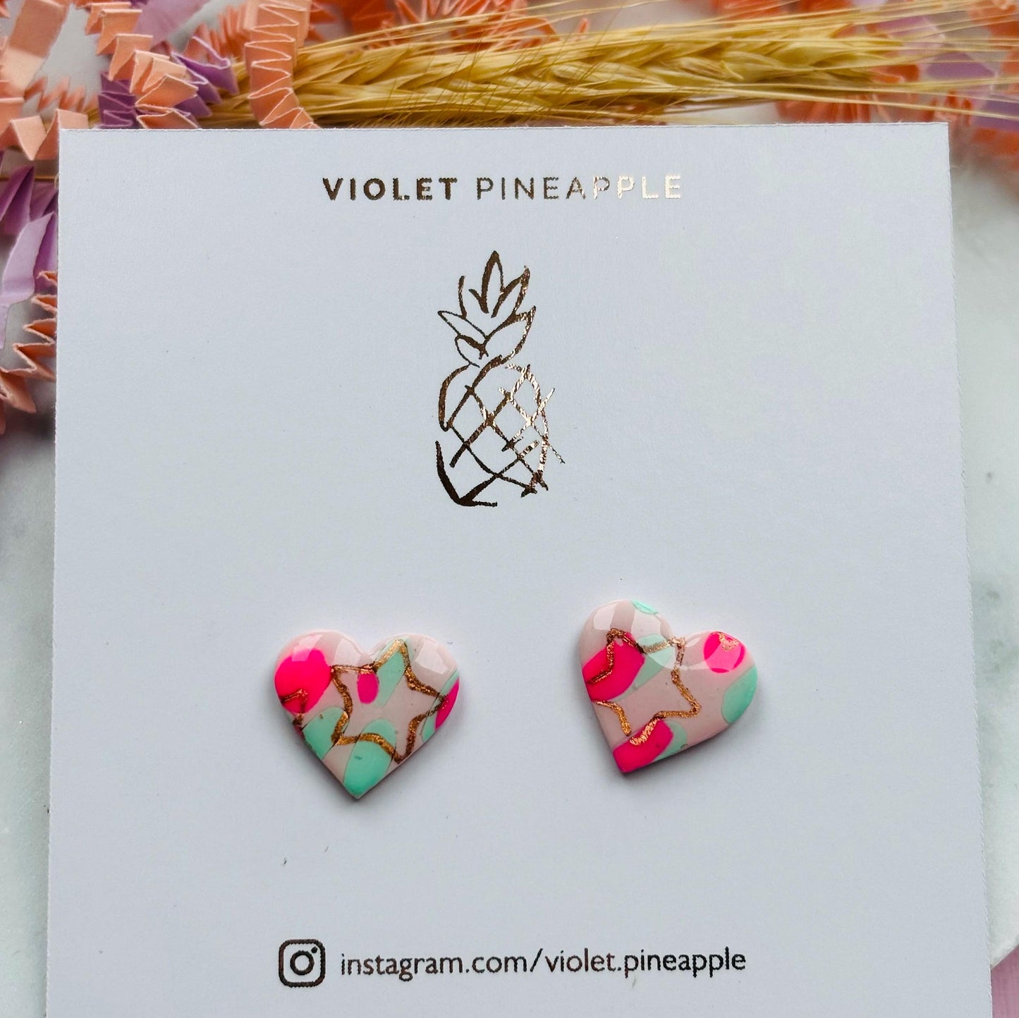 Charming heart stud earrings in pink and mint with a subtle rose gold star detail.