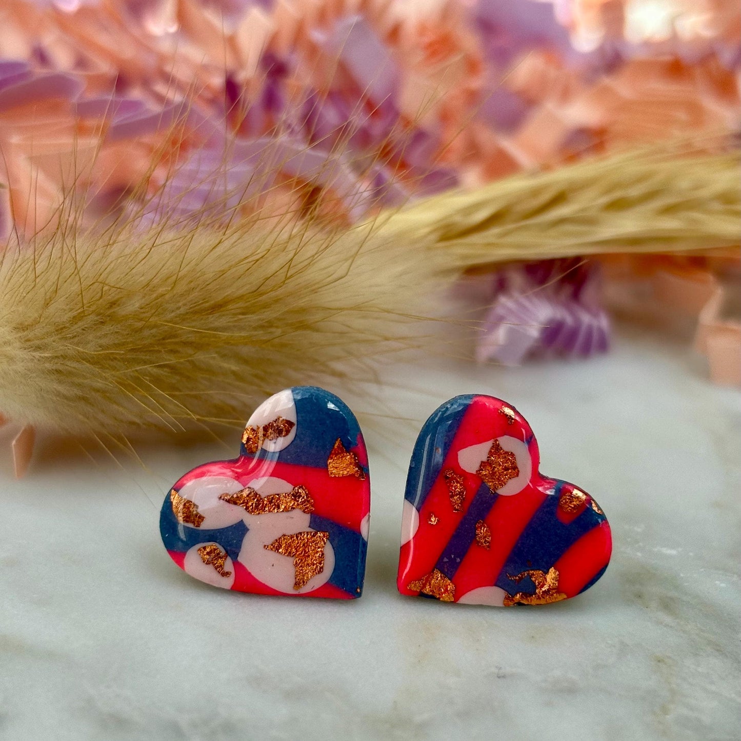 Blue, pink, and rose gold heart stud earrings in a retro 90s style.