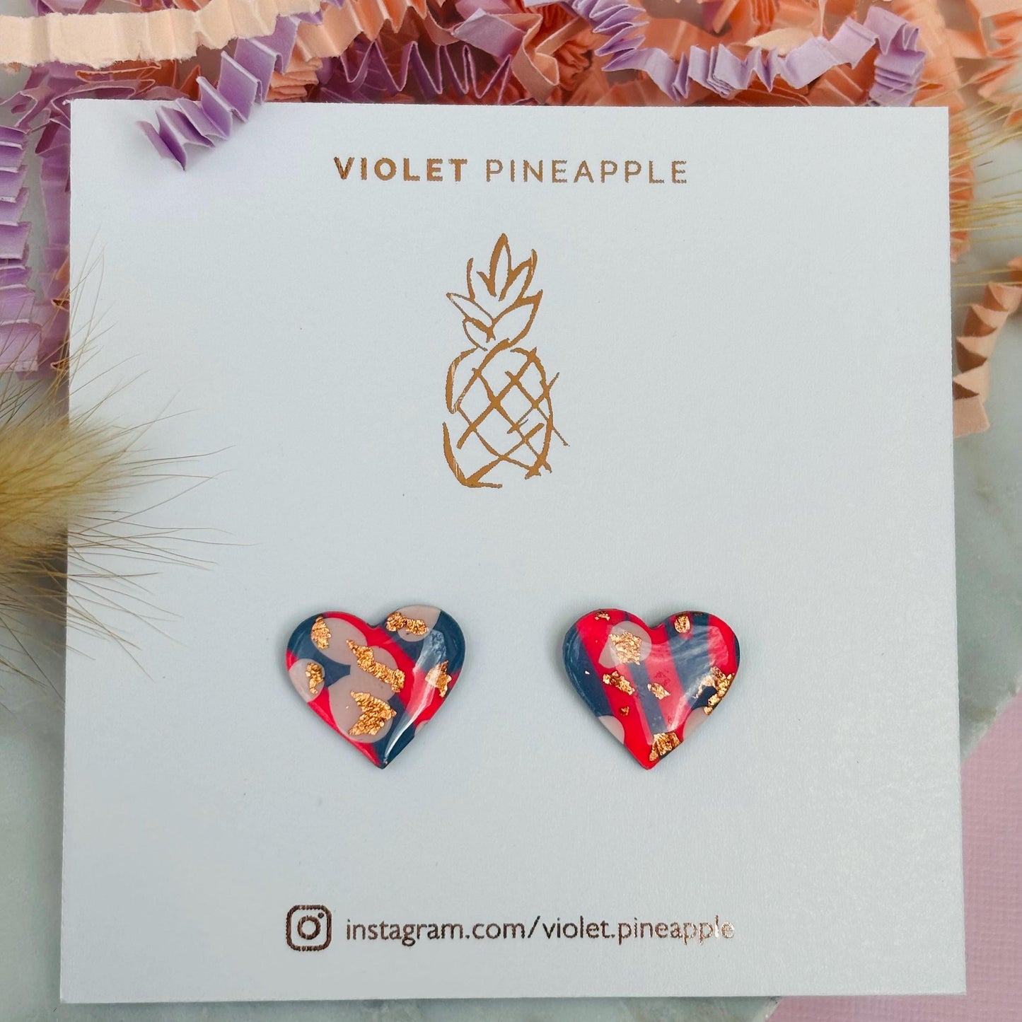 Blue, pink, and rose gold heart stud earrings in a retro 90s style.