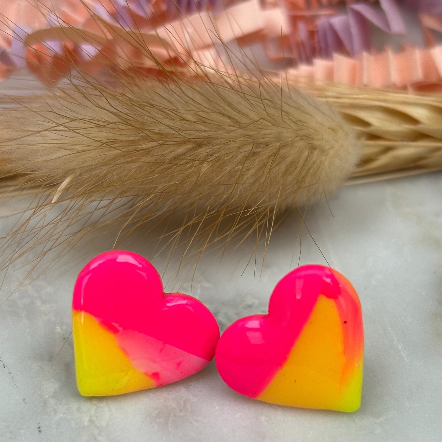 Vibrant 80s-inspired heart-shaped stud earrings, handmade with polymer clay. Features a sunset-inspired color palette of yellow and pink.