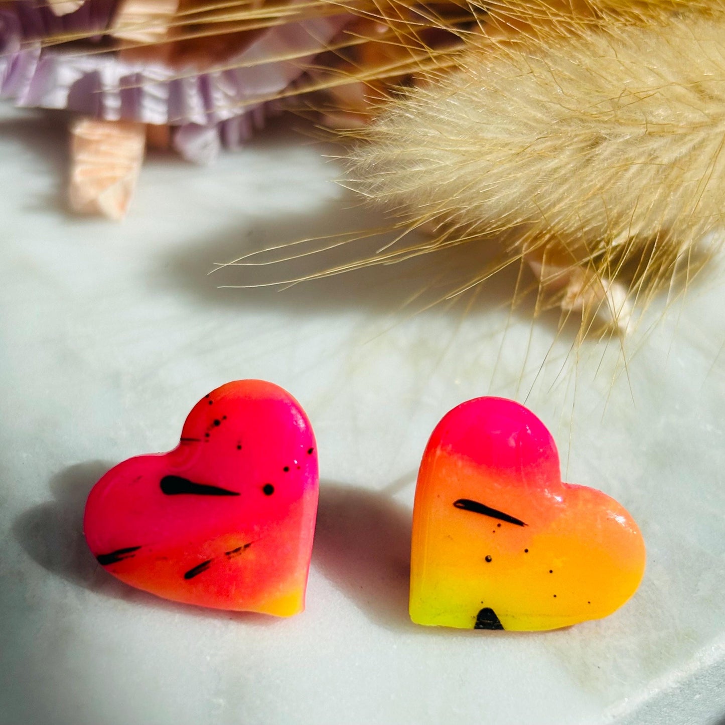 Vibrant 80s disco-inspired heart-shaped stud earrings, handmade with polymer clay. Features a bold color palette with yellow, pink, and black ink splatter.