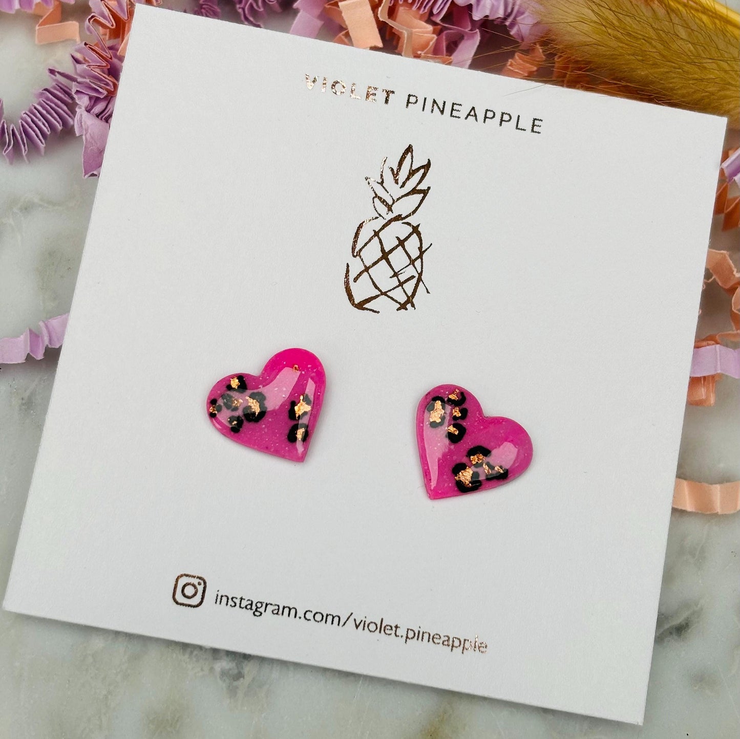 Chic pink heart-shaped stud earrings with a handpainted leopard print, handmade with polymer clay.