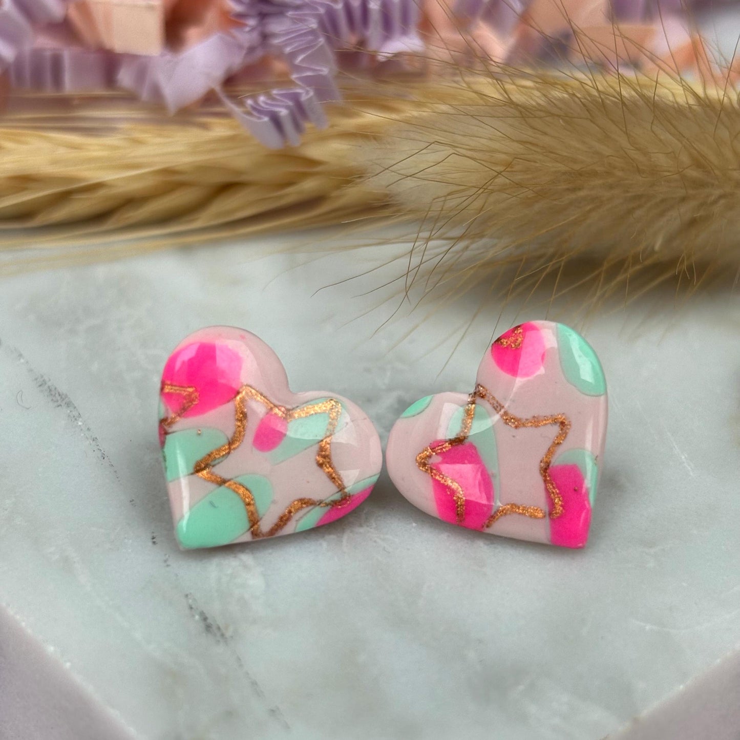 Charming heart stud earrings in pink and mint with a subtle rose gold star detail.
