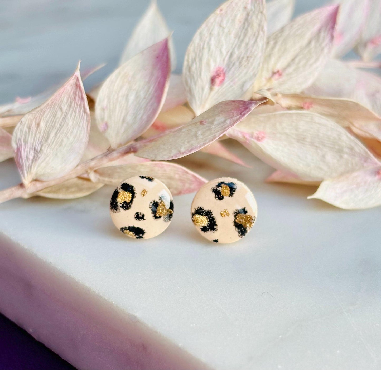 Handcrafted leopard print bracelet and stud earring set with neutral tones and gold accents. Stud earrings are 10mm x 10mm. Set includes an adjustable black corded bracelet. Packaged in a branded gift box