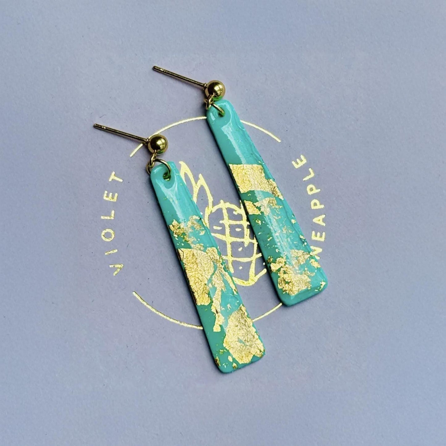 Delicate handmade drop earrings in a soft teal colour with shimmering gold foil accents.