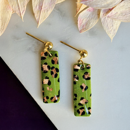 Elegant leopard print drop earrings with gold foil accents, hand-painted and handmade with polymer clay.