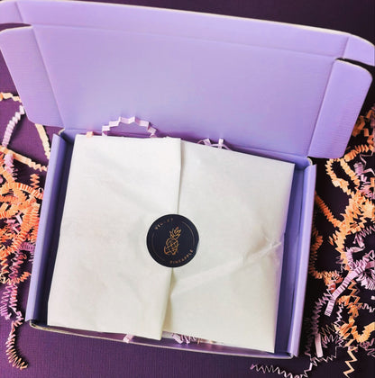 Folded white fabric with a black circular logo in a purple box on a textured surface.