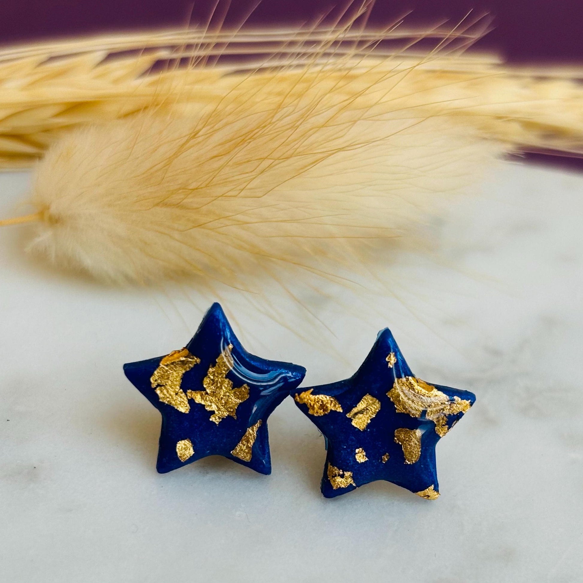 Chic navy blue star-shaped stud earrings with gold foil detailing, handmade with polymer clay.