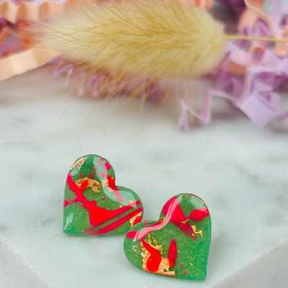 Vibrant neon pink heart-shaped stud earrings, handmade with polymer clay. Features an abstract design with gold foil accents.