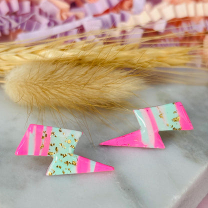 Vibrant 80s ski-inspired lightning bolt stud earrings, handmade with polymer clay. Features soft pink, mint green, and gold leaf accents.
