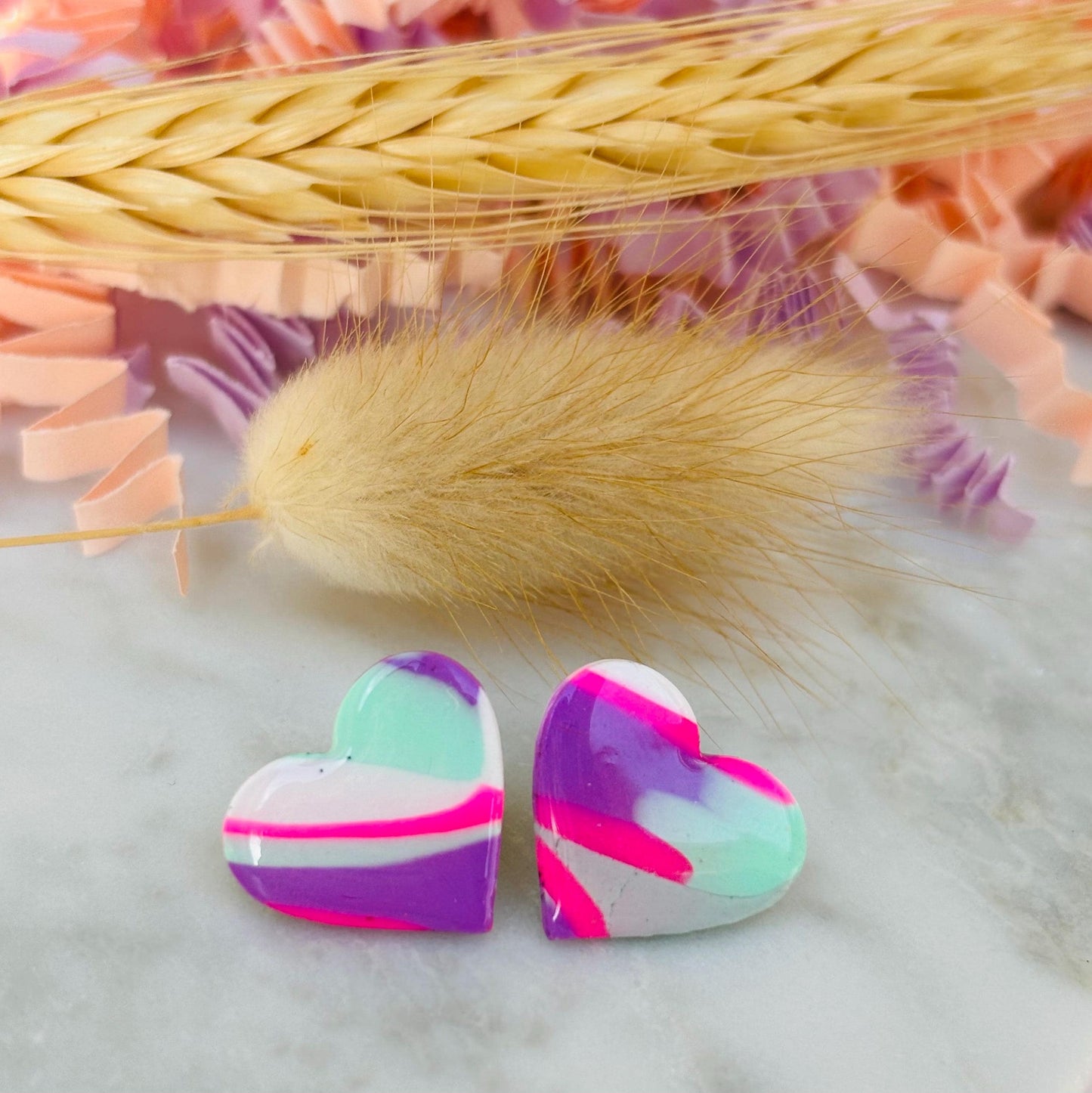 Vibrant 80s-inspired heart-shaped stud earrings, handmade with polymer clay. Features a bold color palette reminiscent of a winter ski slope.