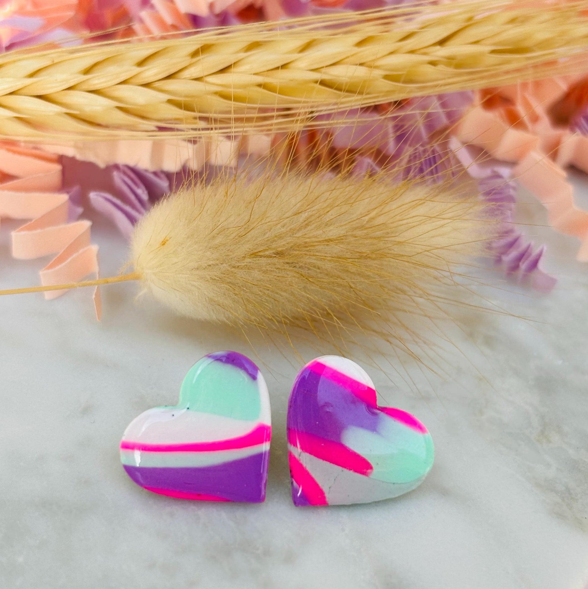 Vibrant 80s-inspired heart-shaped stud earrings, handmade with polymer clay. Features a bold color palette reminiscent of a winter ski slope.