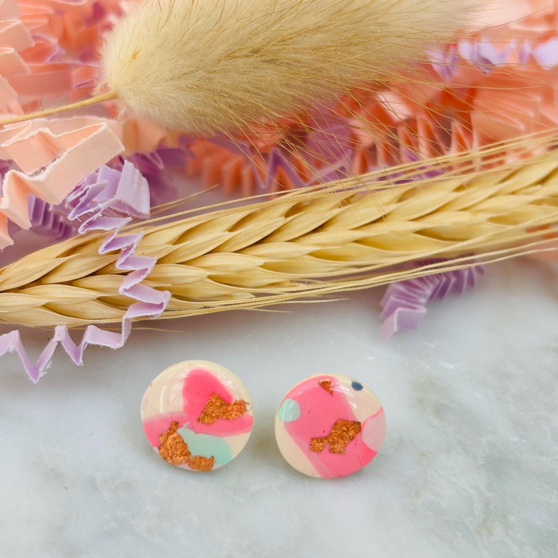Handmade blush pink stud earrings with soft mint pastel undertones and delicate rose gold leaf detail. Finished with a glossy resin for durability and a refined look.