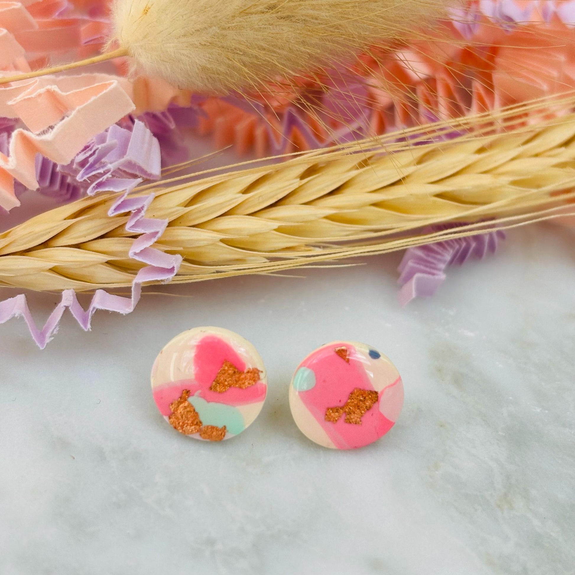 Handmade blush pink stud earrings with soft mint pastel undertones and delicate rose gold leaf detail. Finished with a glossy resin for durability and a refined look.