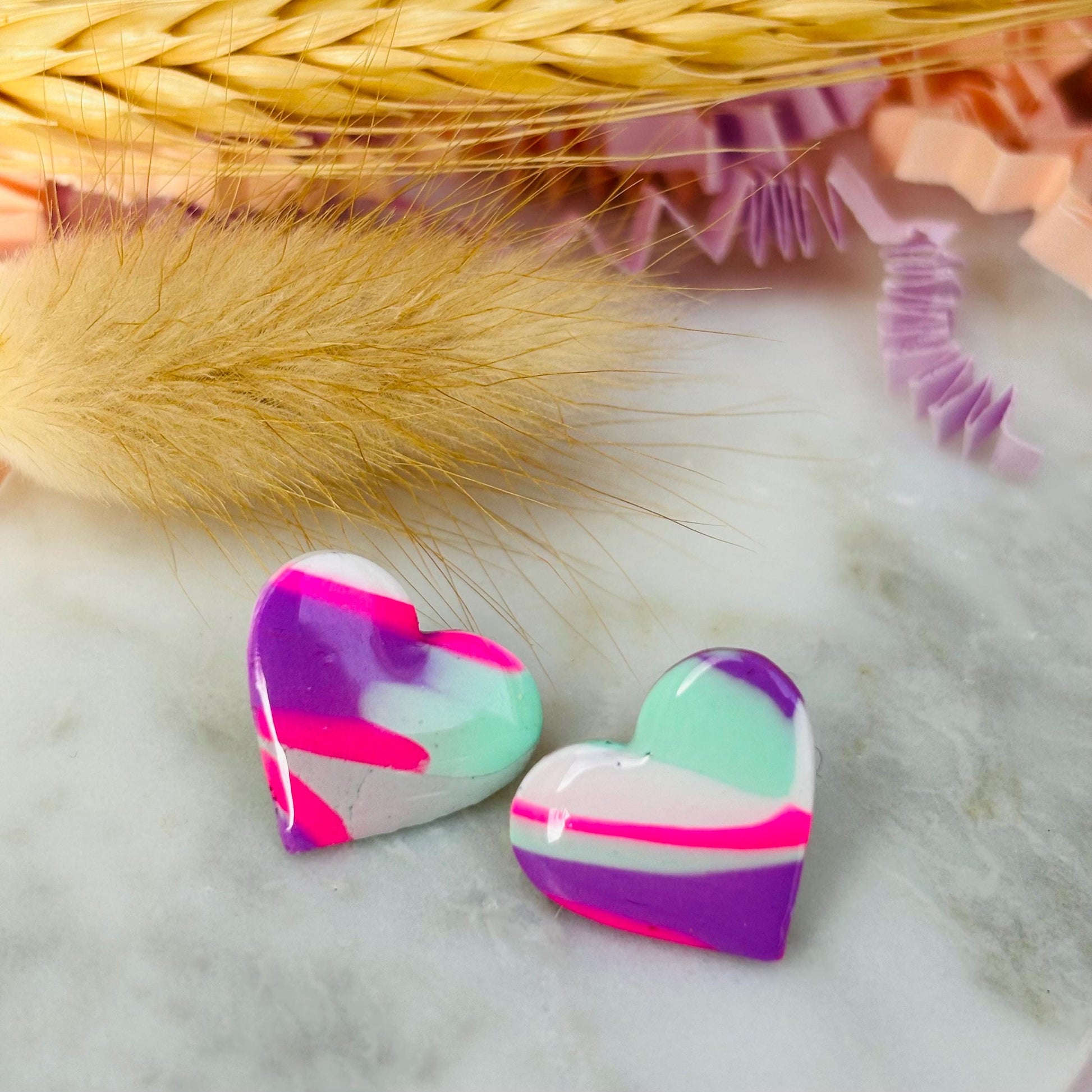 Vibrant 80s-inspired heart-shaped stud earrings, handmade with polymer clay. Features a bold color palette reminiscent of a winter ski slope.