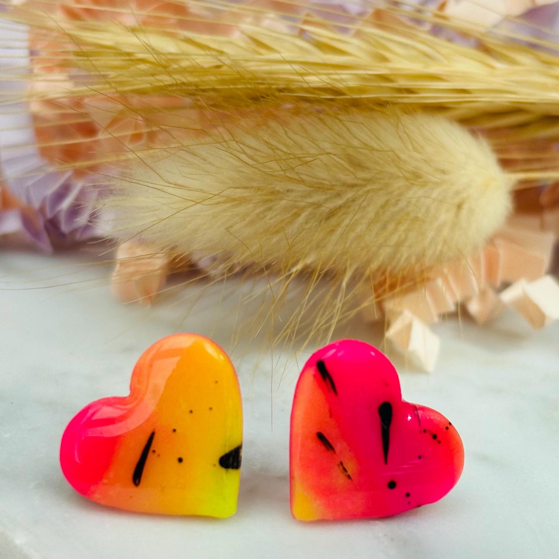 Vibrant 80s disco-inspired heart-shaped stud earrings, handmade with polymer clay. Features a bold color palette with yellow, pink, and black ink splatter.