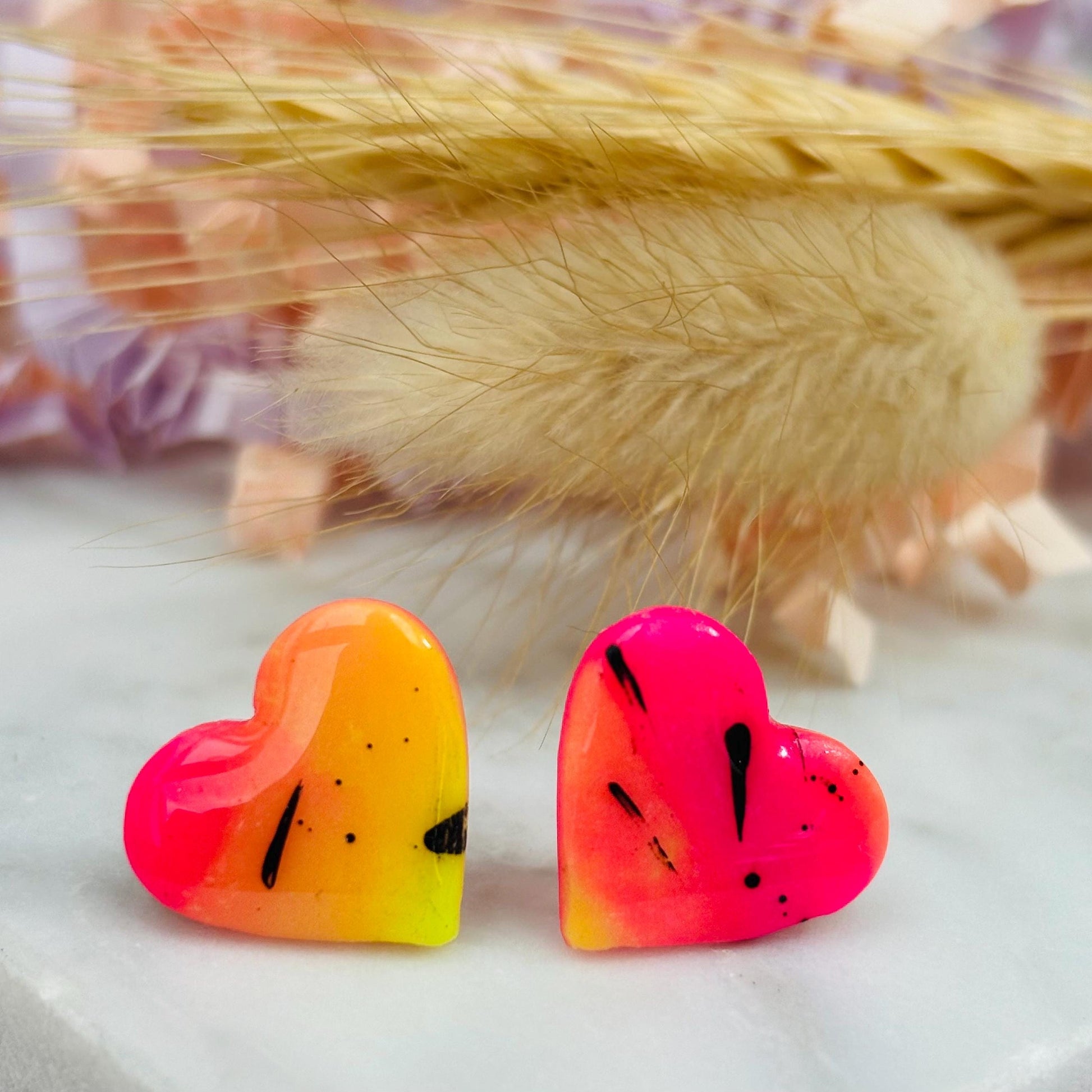 Vibrant 80s disco-inspired heart-shaped stud earrings, handmade with polymer clay. Features a bold color palette with yellow, pink, and black ink splatter.