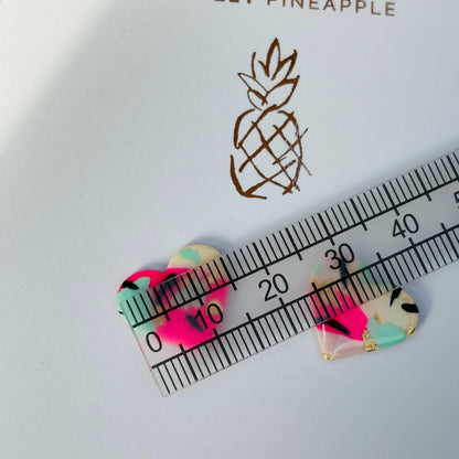 Vibrant 90s punk-inspired heart-shaped stud earrings, handmade with polymer clay. Features neon pink, mint, black ink, and gold leaf accents.