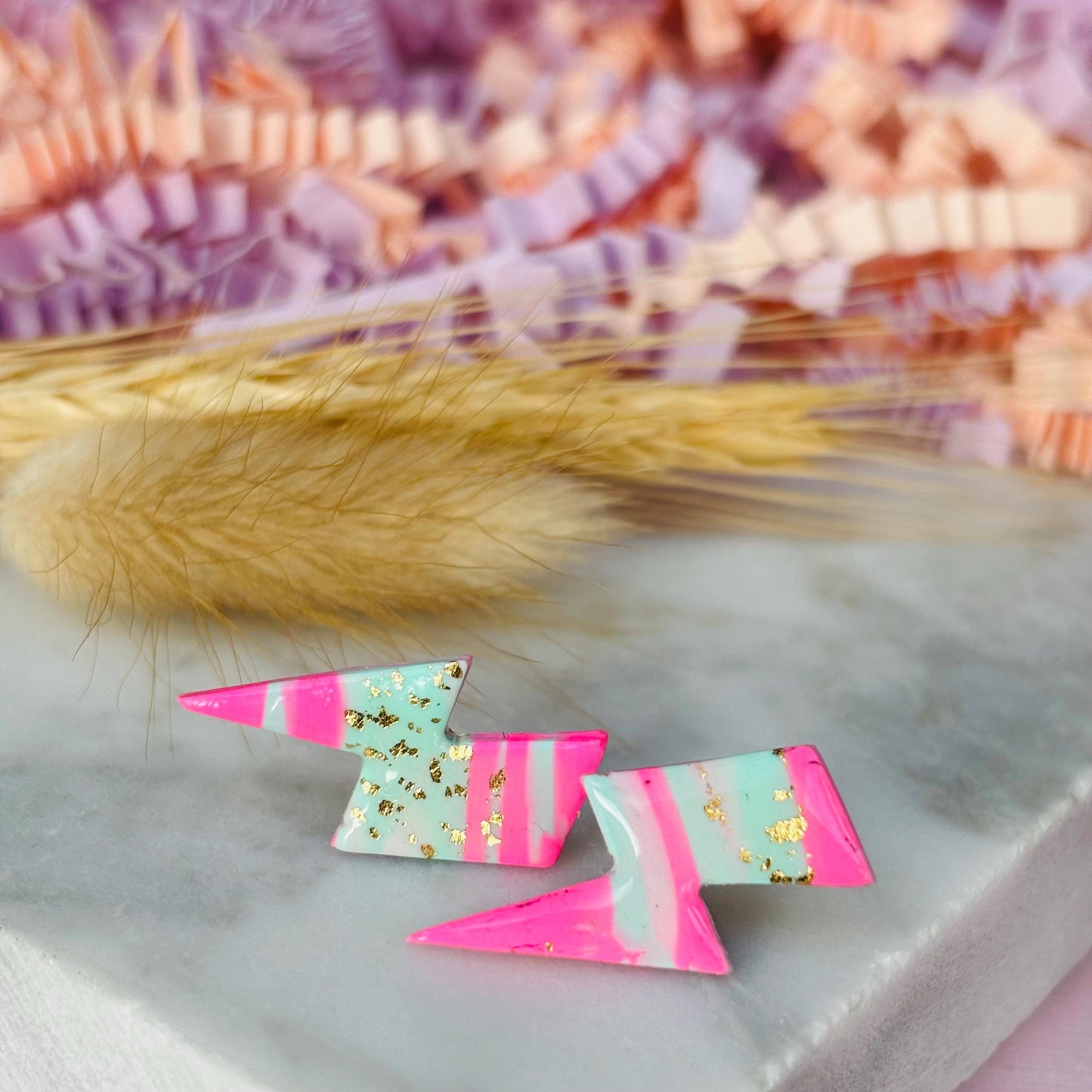 Vibrant 80s ski-inspired lightning bolt stud earrings, handmade with polymer clay. Features soft pink, mint green, and gold leaf accents.