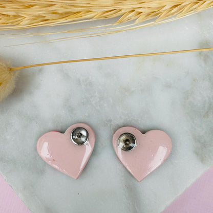 Vibrant pink heart-shaped stud earrings, handmade with polymer clay. Features rose gold leaf accents.
