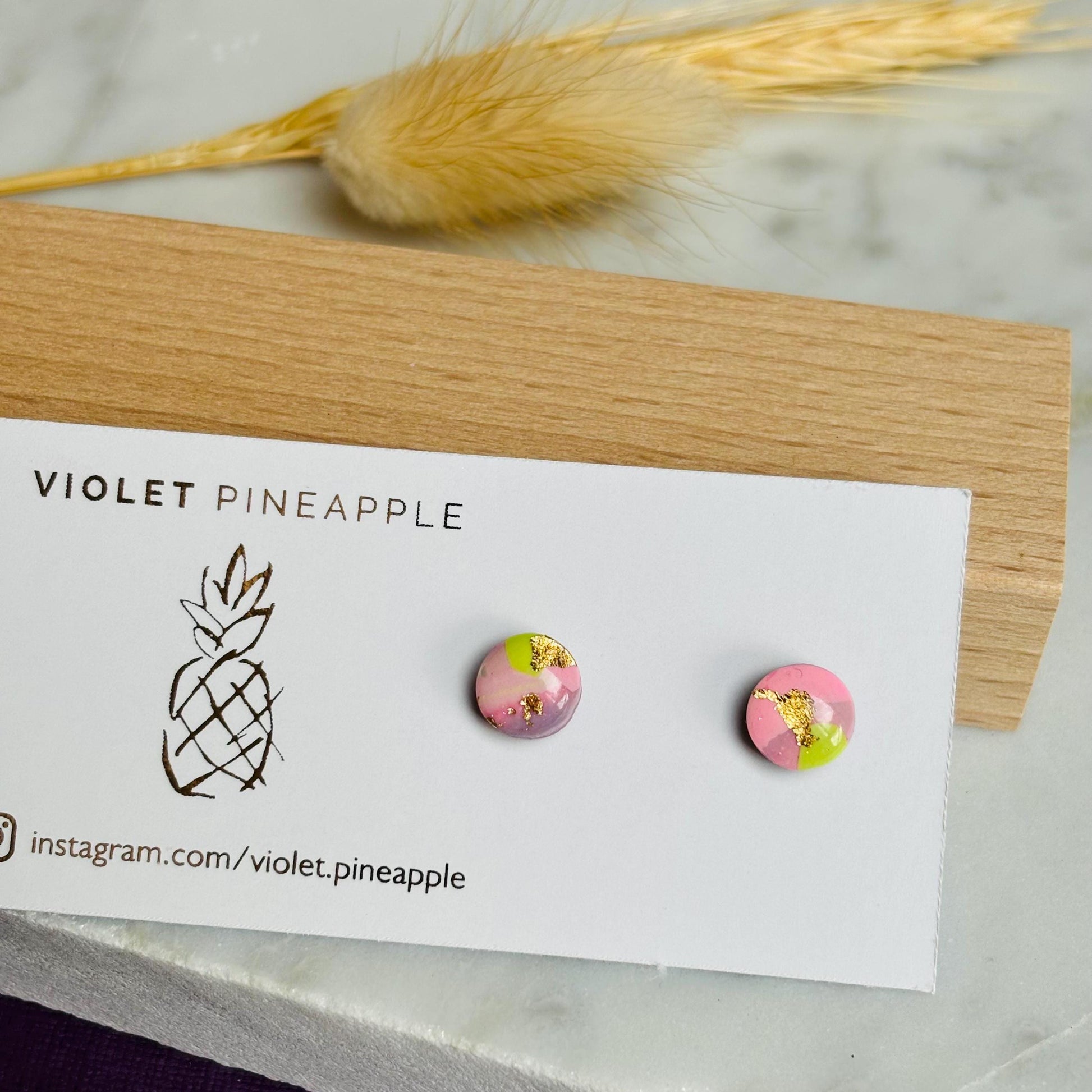 Mini stud earrings with a warm color palette of plum, blush pink, and ochre yellow with gold foil accents, handmade with polymer clay.