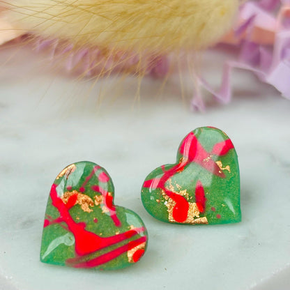Vibrant neon pink heart-shaped stud earrings, handmade with polymer clay. Features an abstract design with gold foil accents.
