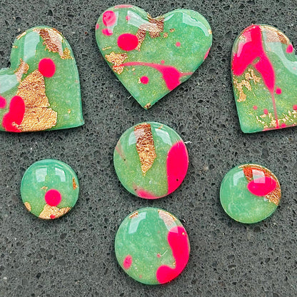 Vibrant neon pink heart-shaped stud earrings, handmade with polymer clay. Features an abstract design with gold foil accents.