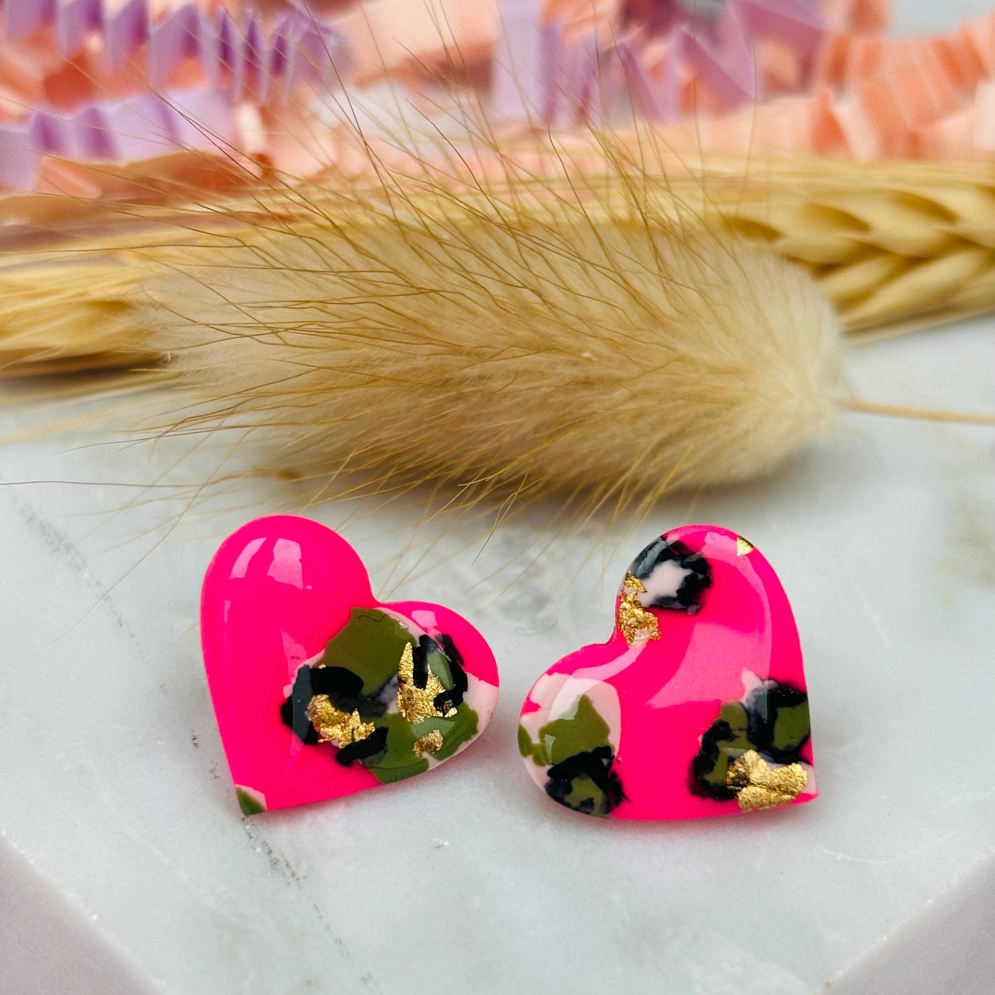 Vibrant neon pink heart-shaped stud earrings with a handpainted leopard print, handmade with polymer clay