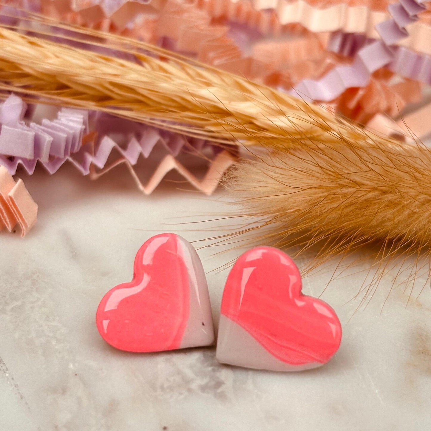 Delicate pink heart-shaped stud earrings, handmade with polymer clay.