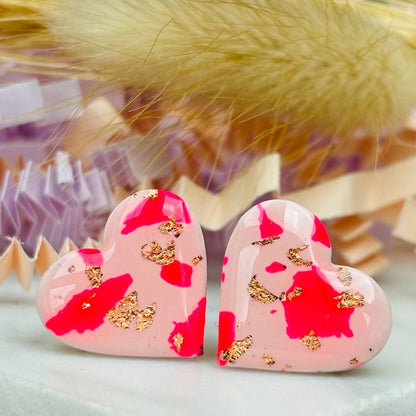 Vibrant pink heart-shaped stud earrings, handmade with polymer clay. Features rose gold leaf accents.