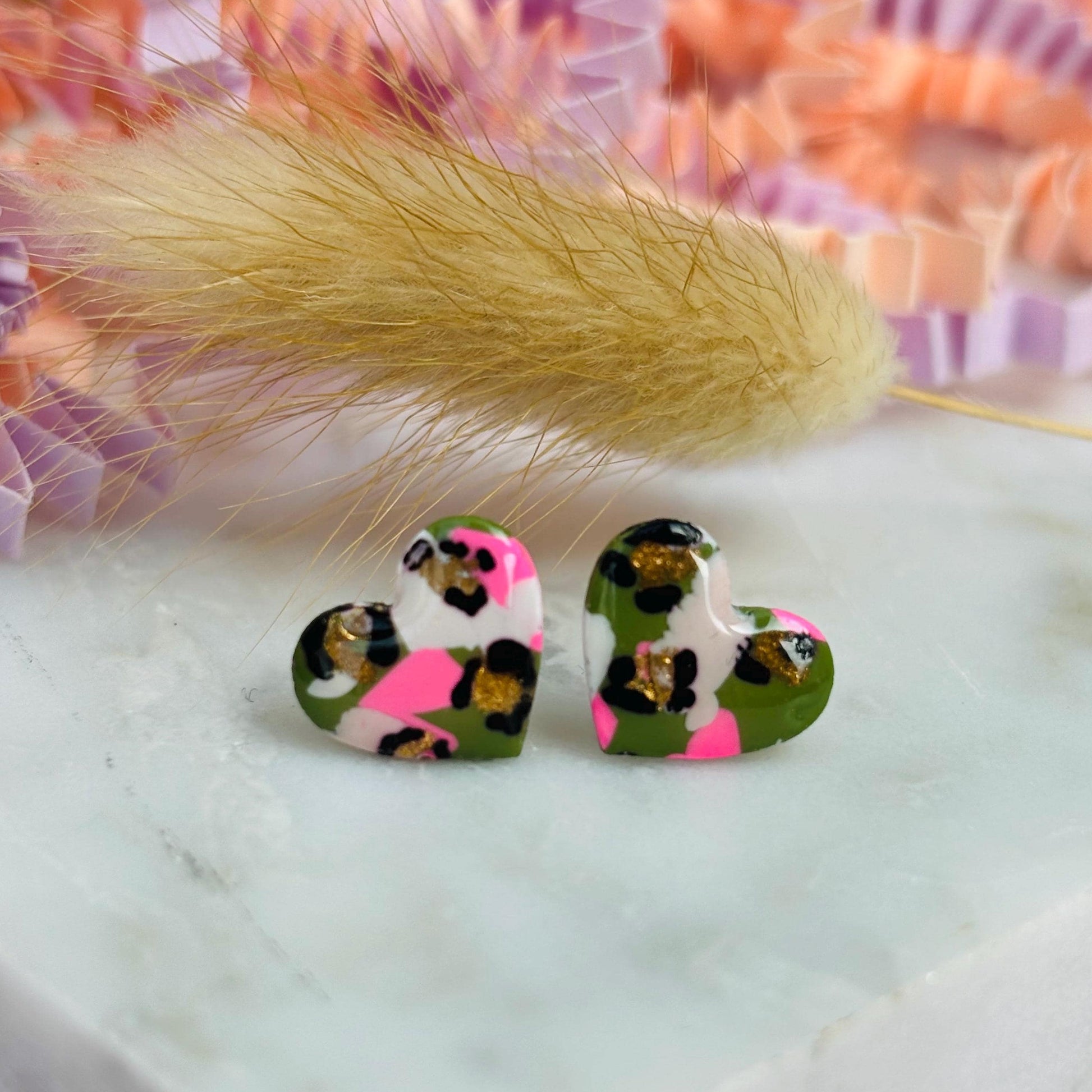 Small leopard print heart stud earrings in green and pink.