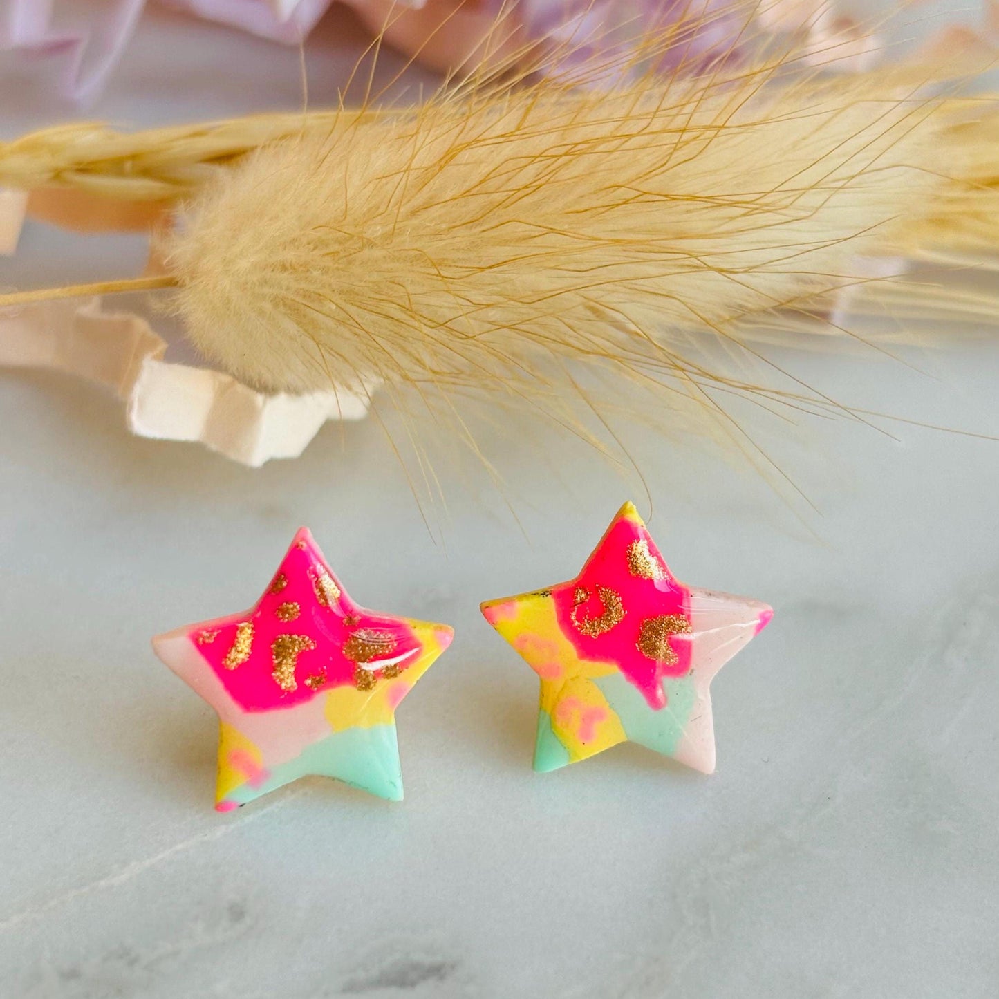 Vibrant 90s-inspired star-shaped stud earrings, handmade with polymer clay. Features a bold leopard print pattern and a mix of vibrant colours.