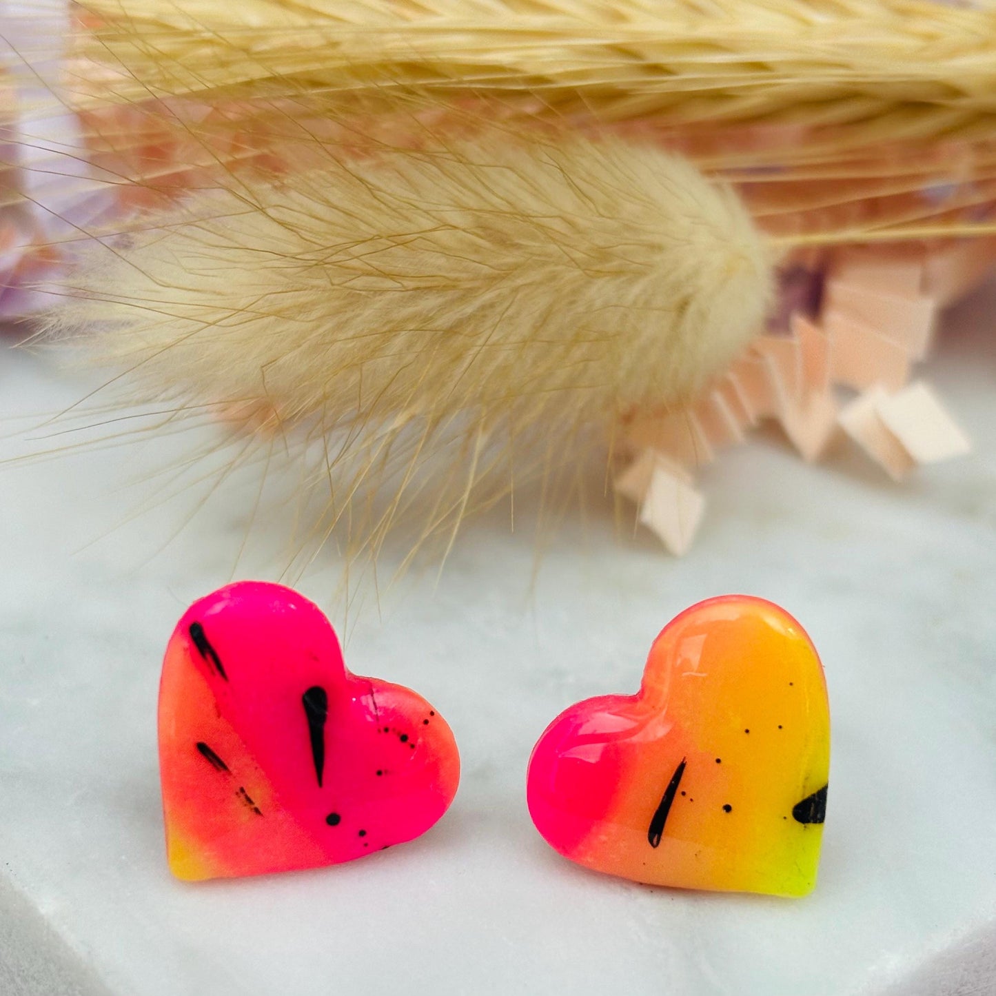 Vibrant 80s disco-inspired heart-shaped stud earrings, handmade with polymer clay. Features a bold color palette with yellow, pink, and black ink splatter.
