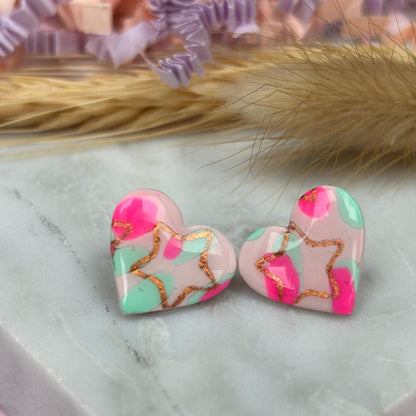 Charming heart stud earrings in pink and mint with a subtle rose gold star detail.