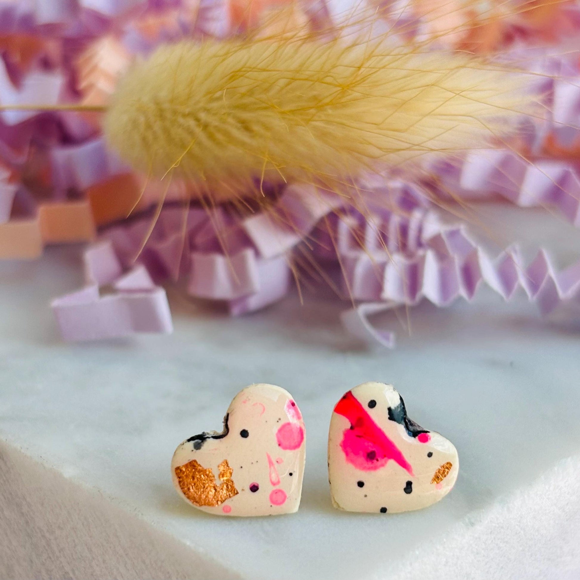 Quirky 90s-inspired neon pink heart-shaped stud earrings, handmade with polymer clay.