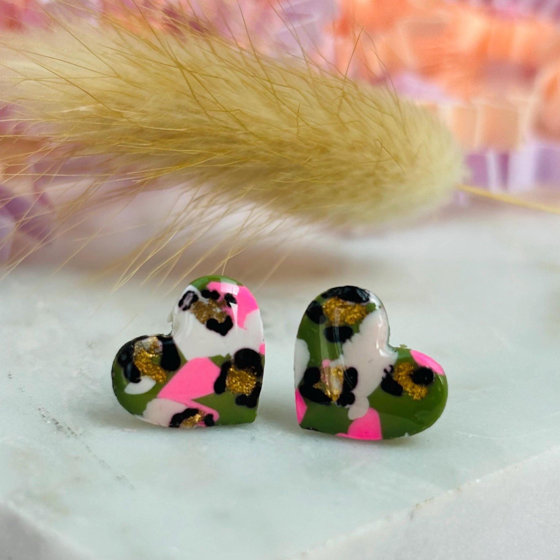 Small leopard print heart stud earrings in green and pink.