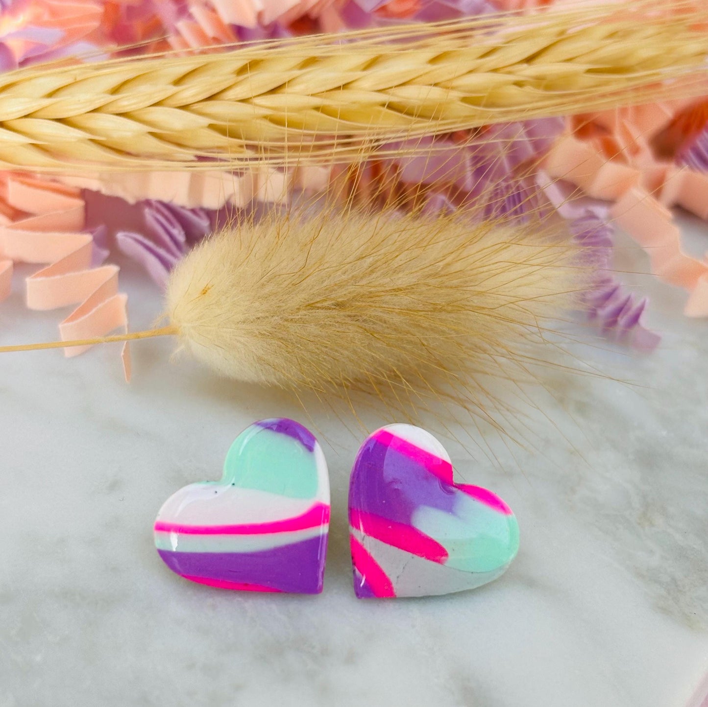 Vibrant 80s-inspired heart-shaped stud earrings, handmade with polymer clay. Features a bold color palette reminiscent of a winter ski slope.