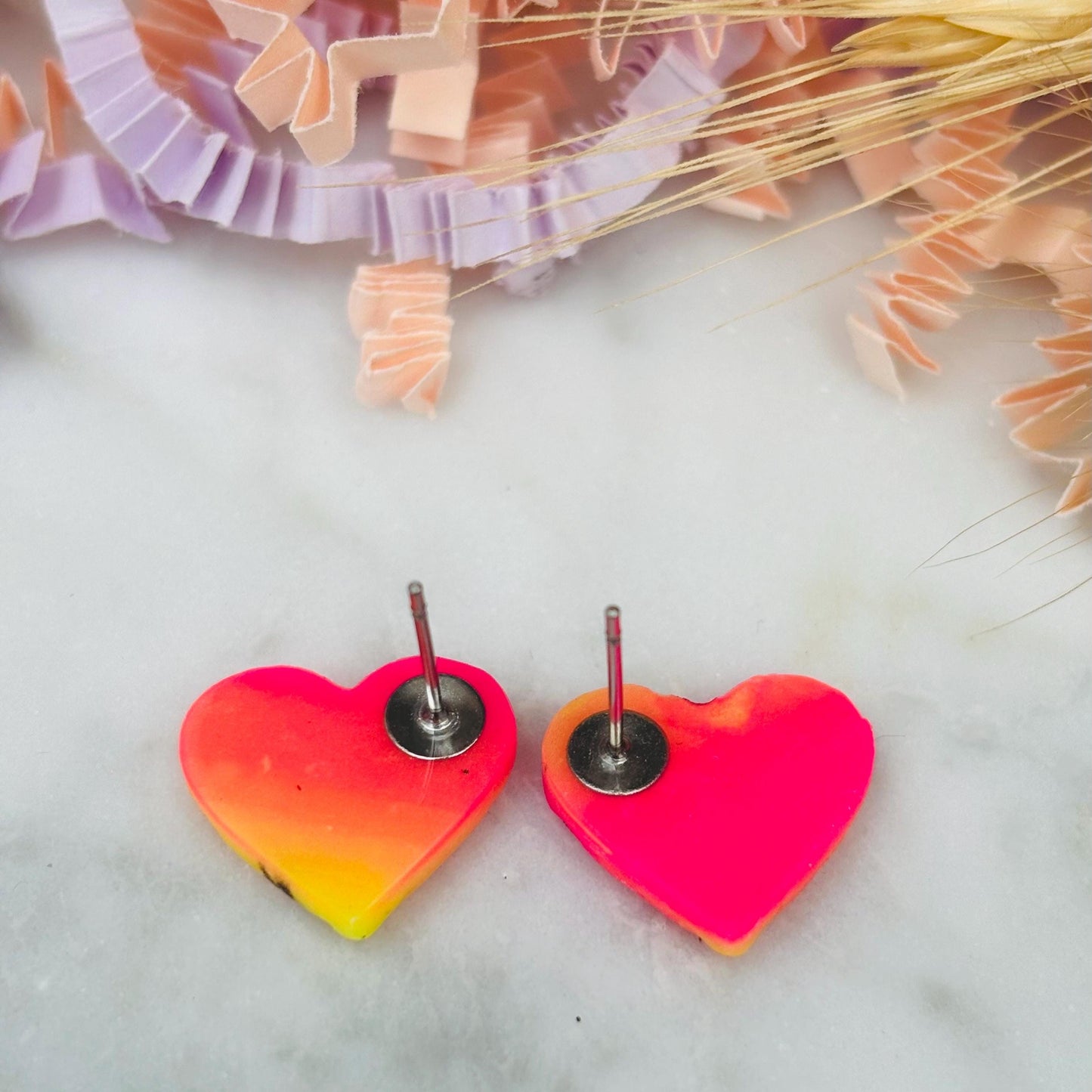 Vibrant 80s disco-inspired heart-shaped stud earrings, handmade with polymer clay. Features a bold color palette with yellow, pink, and black ink splatter.