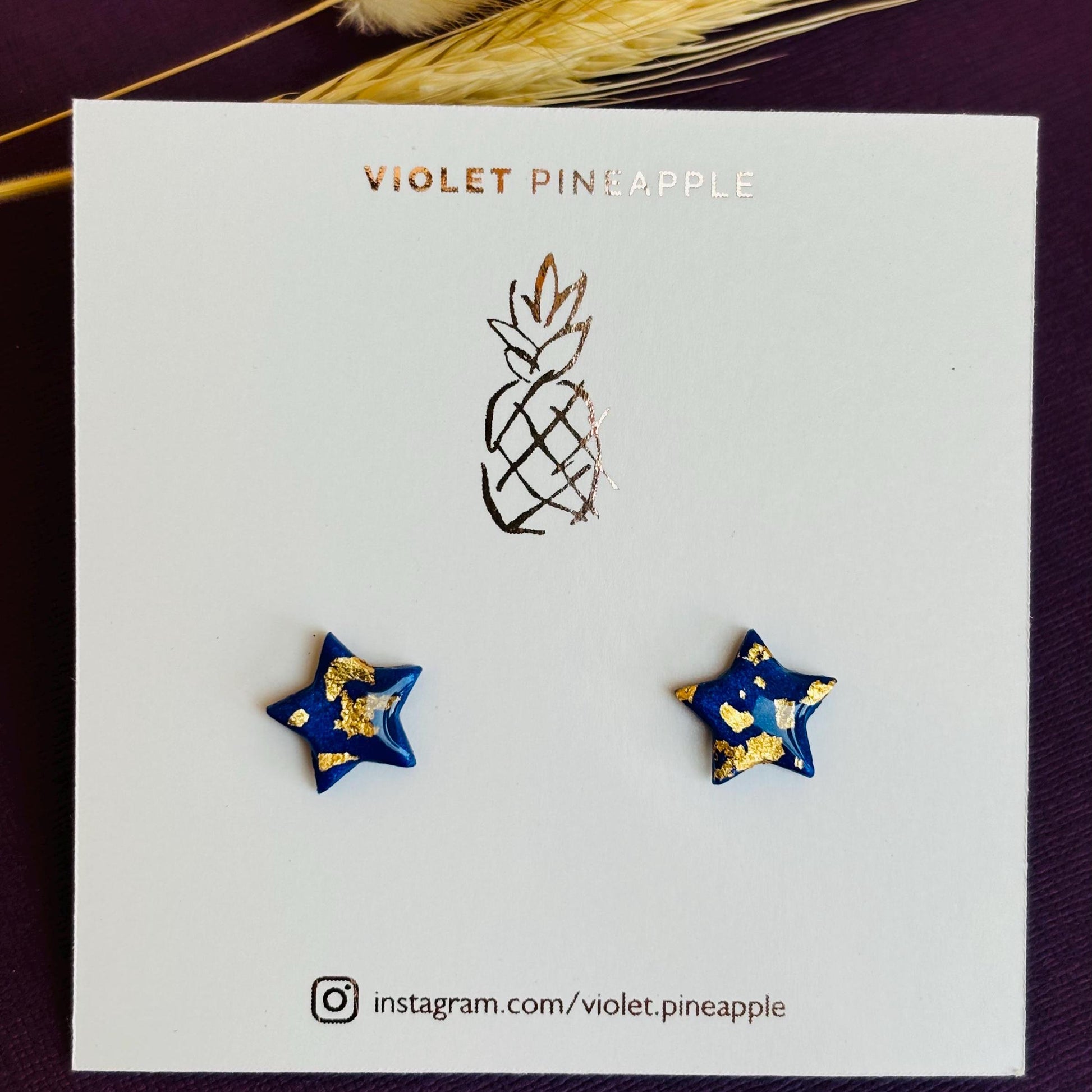 Chic navy blue star-shaped stud earrings with gold foil detailing, handmade with polymer clay.