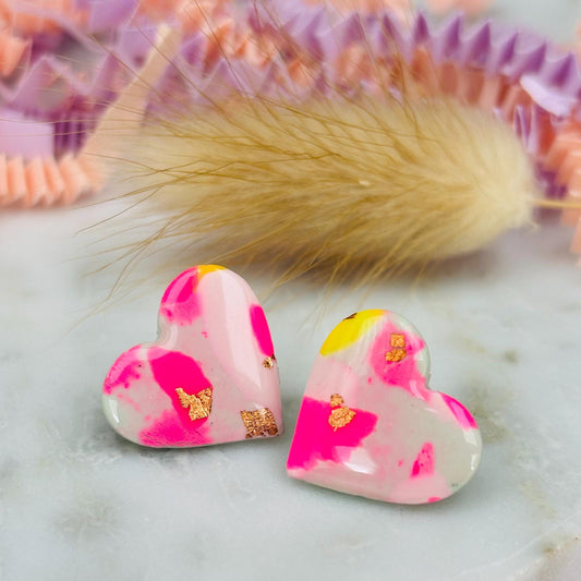 Delicate pastel-coloured heart-shaped stud earrings, handmade with polymer clay. Features soft pink, and yellow with gold leaf accents.