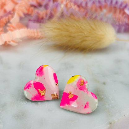 Delicate pastel-coloured heart-shaped stud earrings, handmade with polymer clay. Features soft pink, and yellow with gold leaf accents.