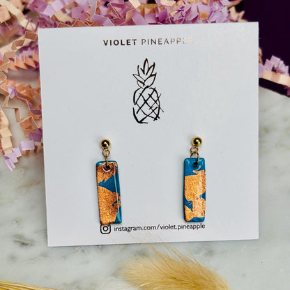 Elegant teal drop earrings with rose gold foil accents, handmade with polymer clay.