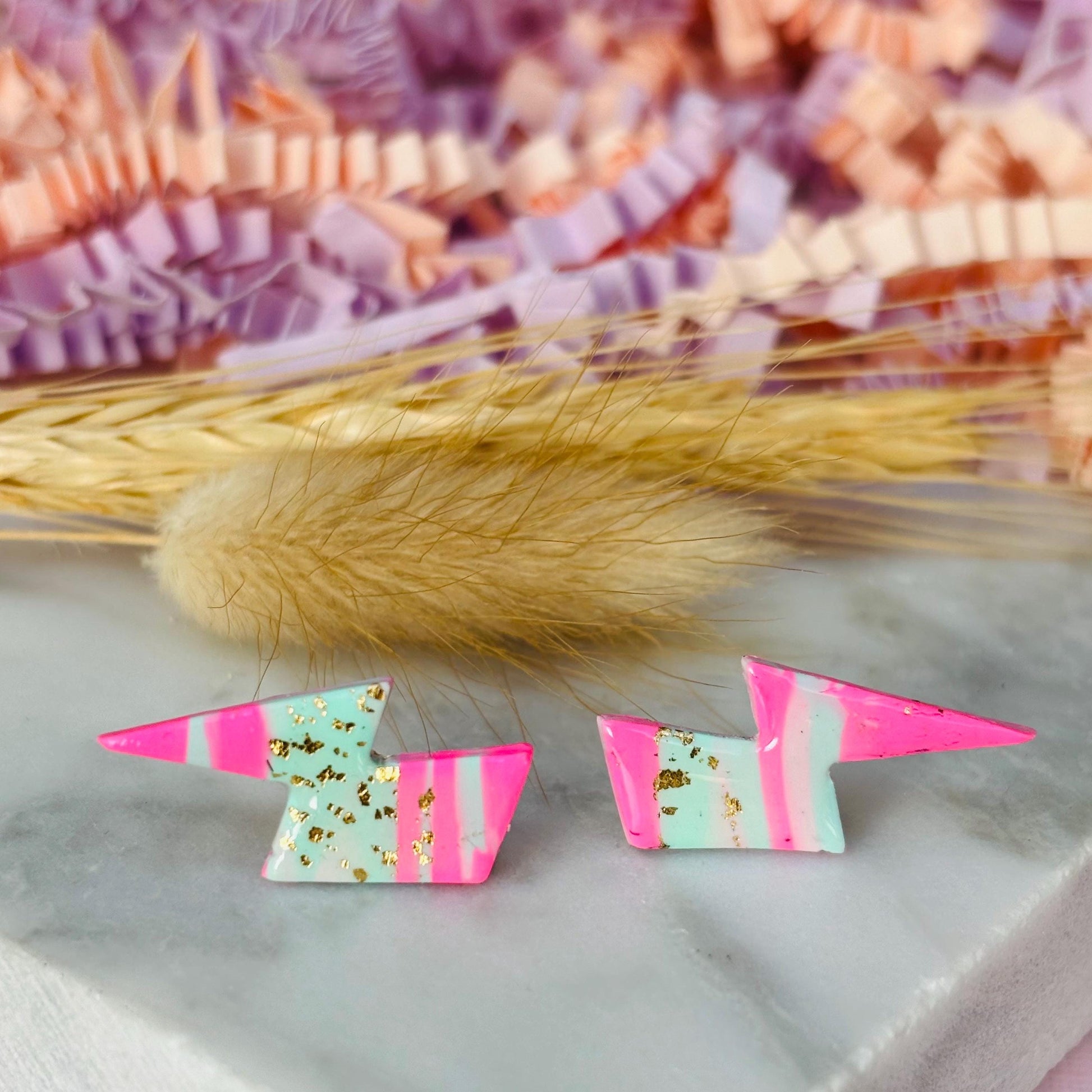 Vibrant 80s ski-inspired lightning bolt stud earrings, handmade with polymer clay. Features soft pink, mint green, and gold leaf accents.