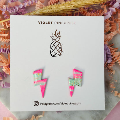 Vibrant 80s ski-inspired lightning bolt stud earrings, handmade with polymer clay. Features soft pink, mint green, and gold leaf accents.